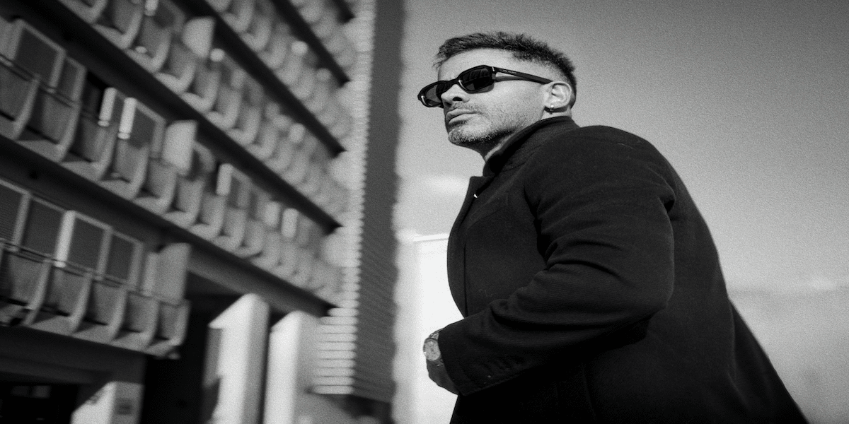 Image commercially licensed from https://unsplash.com/photos/a-man-in-a-coat-and-sunglasses-standing-in-front-of-a-building-Vj-2MB9YN34