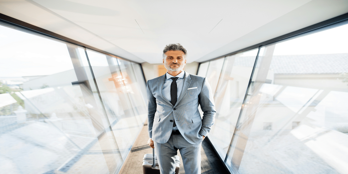 Image commercially licensed from https://unsplash.com/photos/mature-businessman-walking-in-the-corridor-with-suitcase-travelling-H8d_vguMFzA